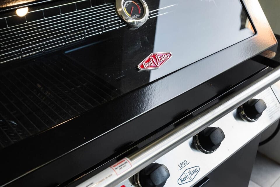 A close-up of a black barbecue grill with a temperature gauge on top and a `Beef Eater` logo prominently displayed on the side.