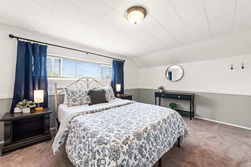 Cozy bedroom w/ patterned bedding, soft lighting & window views for a relaxing stay