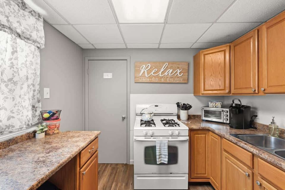 L-shaped kitchen w/ wood cabinets, tiled backsplash & everything within easy reach