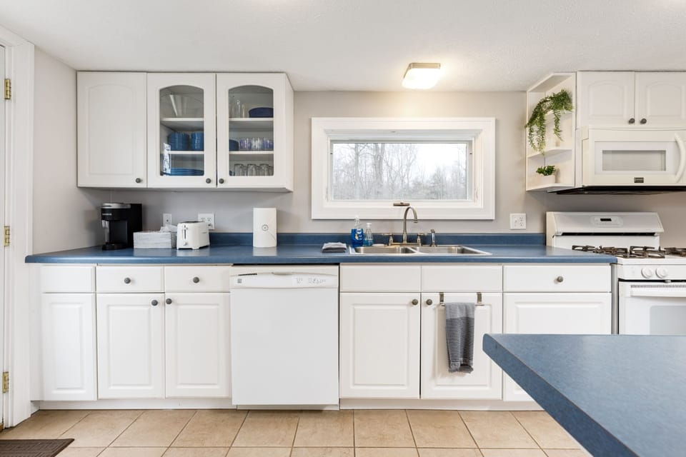 Step into our kitchen, where classic elegance meets modern charm. With pristine white cabinetry contrasting deep blue countertops, bathed in natural light from the glass door, it's a harmonious fusion of style and functionality that's sure to inspire culinary creativity.