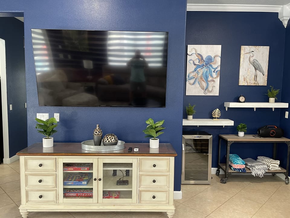 Open concept living and dining room with 75 inch TV and wine/beverage fridge.