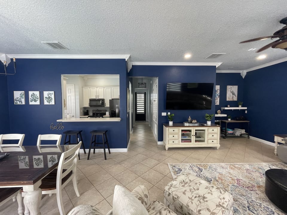Open concept living and dining room with 75 inch TV and wine/beverage fridge.