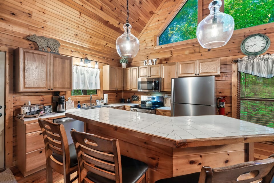 Rustic kitchen with modern appliances, wood accents, and forest views.