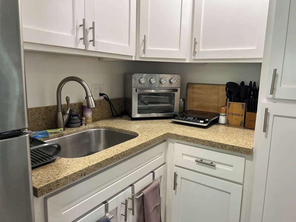 Kitchenette with full size fridge, microwave, sink, air fryer/toaster oven, and burner.