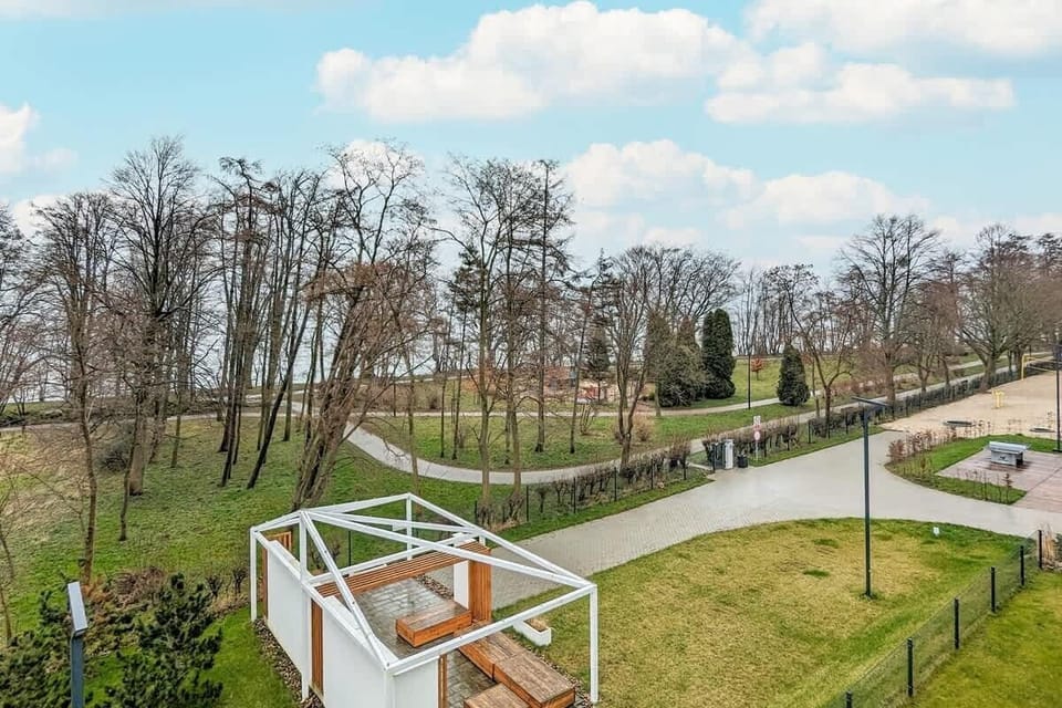 A scenic outdoor view showcases a lush green landscape with trees and a building in the distance.
