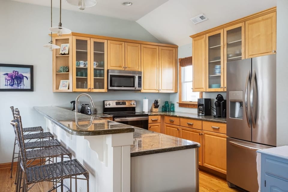 Top Level Fully Equipped Kitchen with refrigerator, Microwave, Stove, Dishwasher, Coffee maker, Blender, and Breakfast Bar Seating, Creating a Welcoming Space for Cooking, Dining, and Socializing