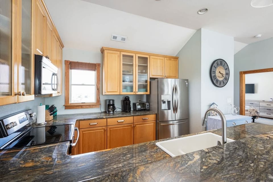 Top Level Fully Equipped Kitchen with refrigerator, Microwave, Stove, Dishwasher, Coffee maker, Blender, and Breakfast Bar Seating, Creating a Welcoming Space for Cooking, Dining, and Socializing