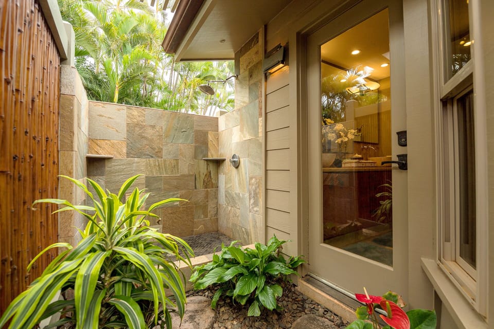 Experience ultimate privacy and relaxation with this beautifully designed outdoor shower, surrounded by lush tropical plants and bamboo accents.