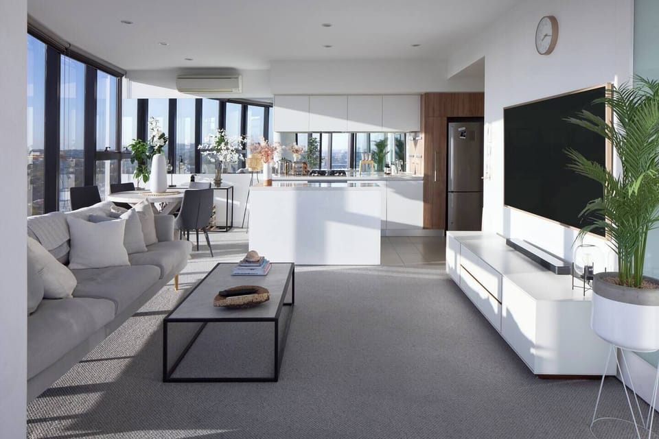 The living area boasts dapper designs, accented by a marble-look coffee table, sleek entertainment unit, large wall-mounted TV, long smokey-grey lounge and an unbeatable skyline backdrop.
