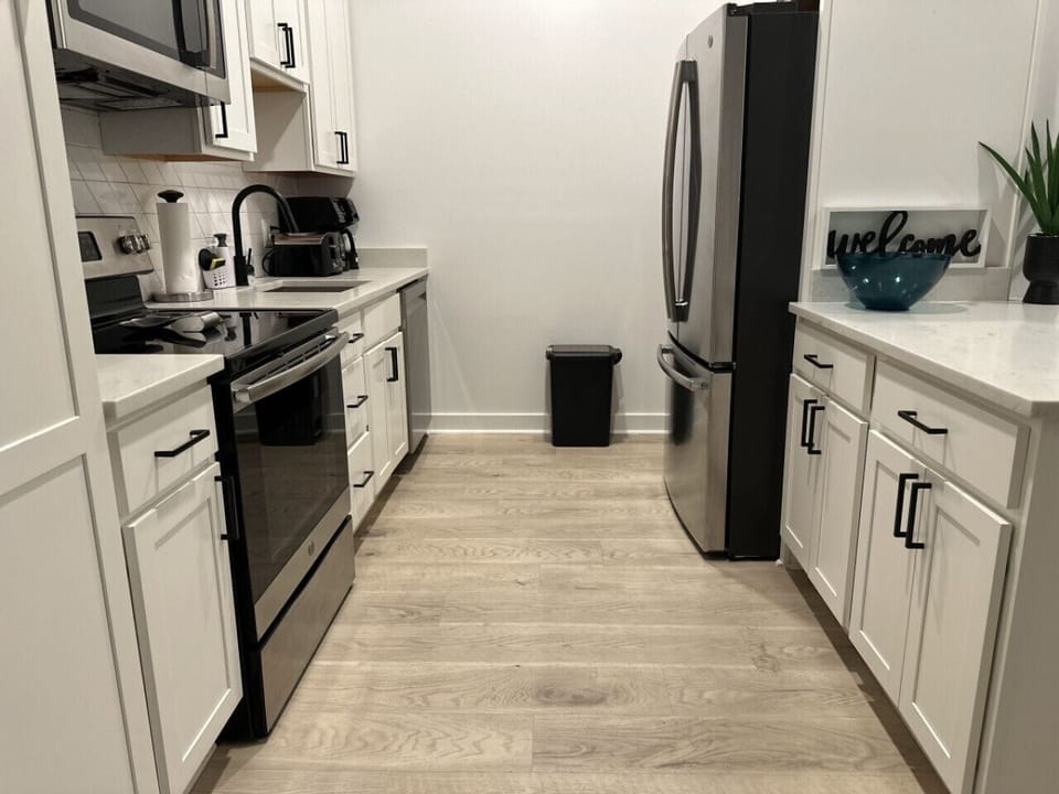 A modern and well-equipped kitchen with white cabinetry, stainless steel appliances, and coordinated countertops, creating a clean and inviting culinary space
