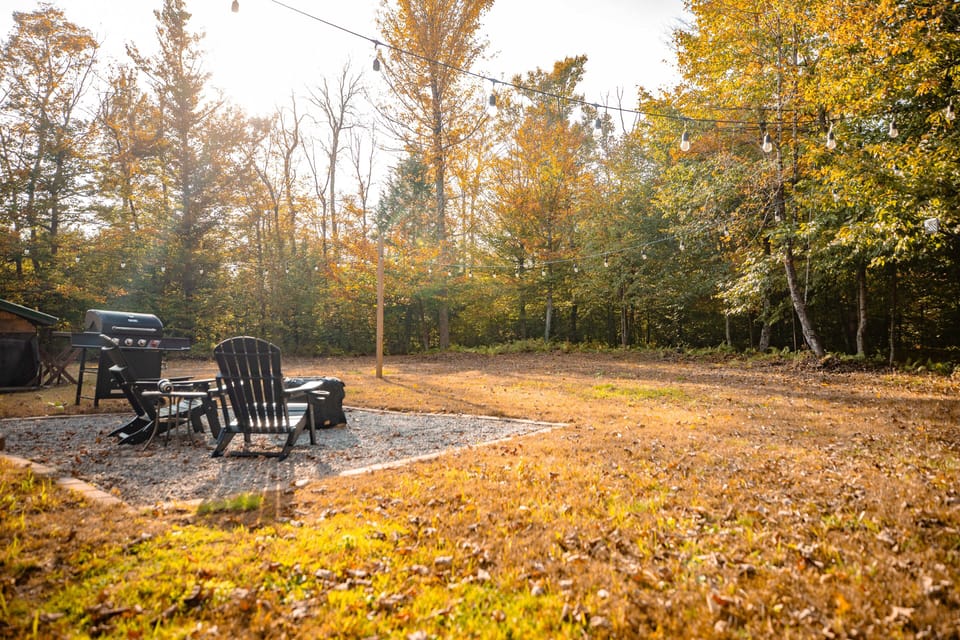 Gather around the fire pit with chairs and grill in a peaceful setting.