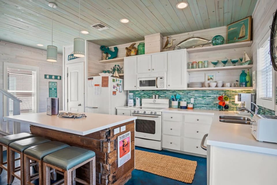 Whitewashed wood tones meet ocean hues in this cute kitchen, complete with island seating for casual dining.