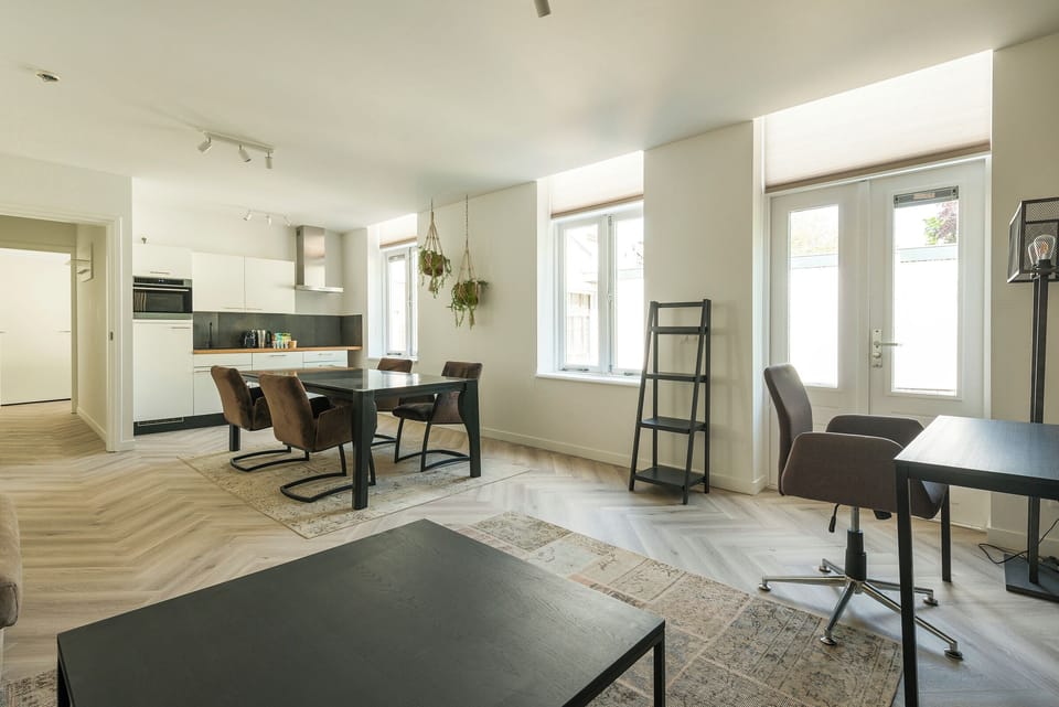 A seamless blend of living and dining areas with natural light streaming in through large windows, creating a warm and modern ambiance.