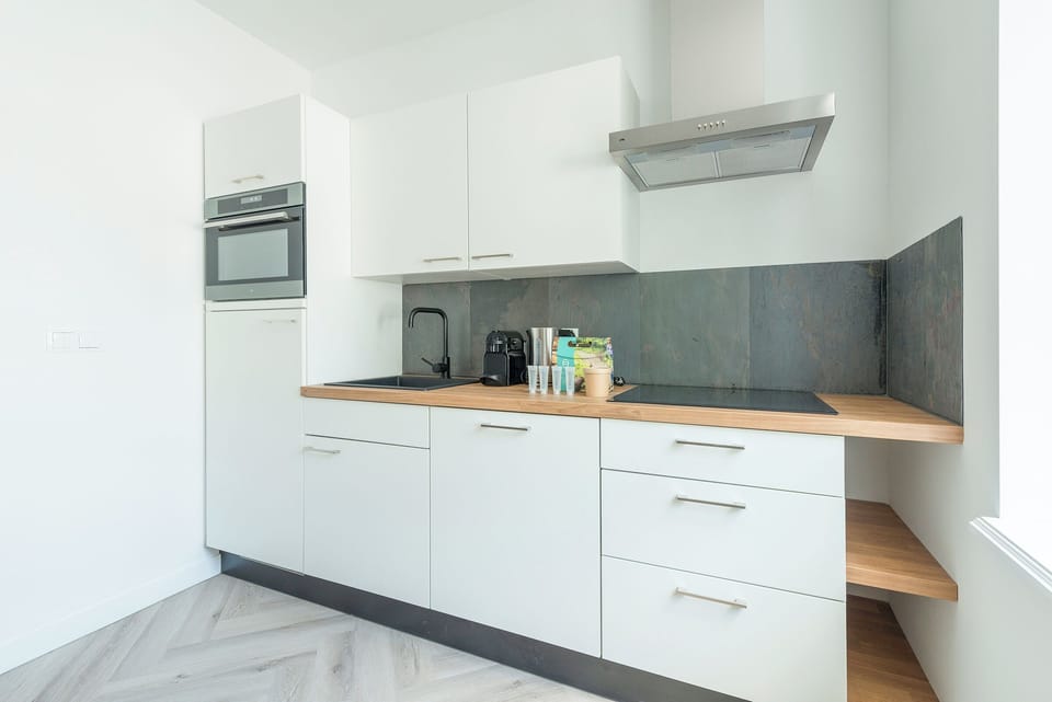 A compact yet functional kitchen featuring modern cabinetry, a sleek countertop, and essential appliances for your culinary needs.