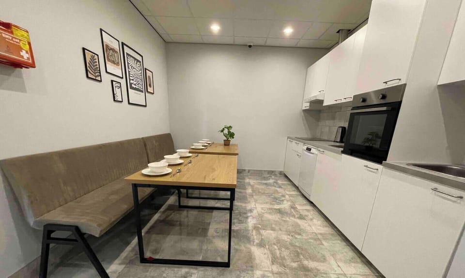 The shared kitchen is thoughtfully designed, featuring a long bench for group dining and a well-equipped cooking area. The modern layout ensures a practical and inviting space for guests to prepare meals and dine together.