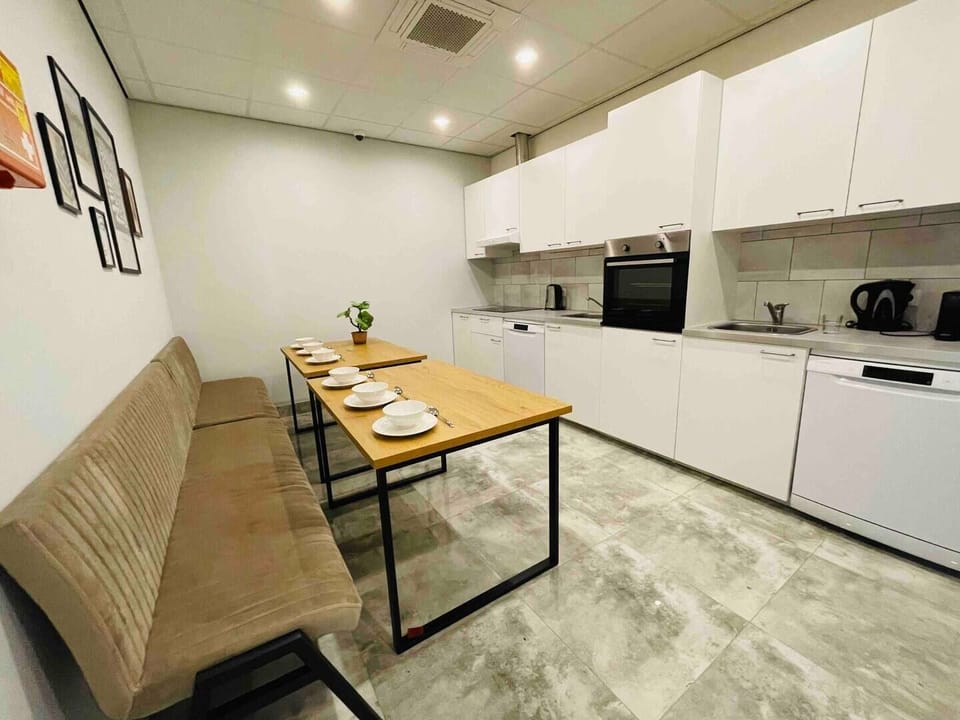 Modern shared kitchen featuring a long dining table, sleek appliances, and ample space for cooking and socializing.