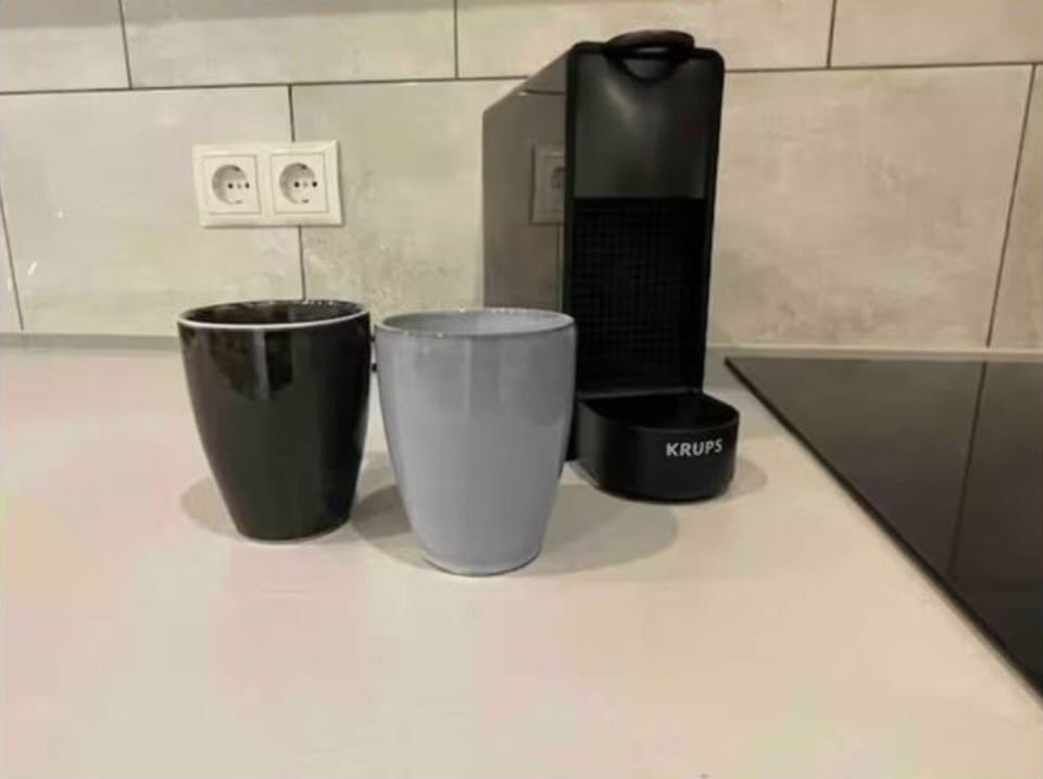  featuring a Krups coffee machine, two stylish mugs in black and gray, tiled backsplash, and sleek neutral tones for a clean, contemporary look.