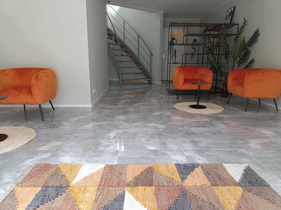 Spacious lounge area with vibrant orange seating, modern accents, and a stylish geometric rug, perfect for relaxation or casual meetings.
