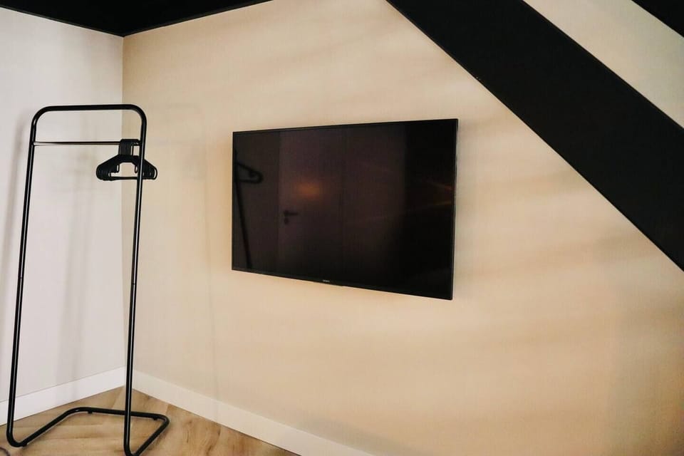 A minimalist corner with a sleek TV mounted on the wall and a modern clothes rack.
