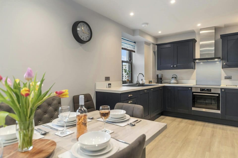Modern kitchen with dark cabinets, built-in oven and dining table set for eight