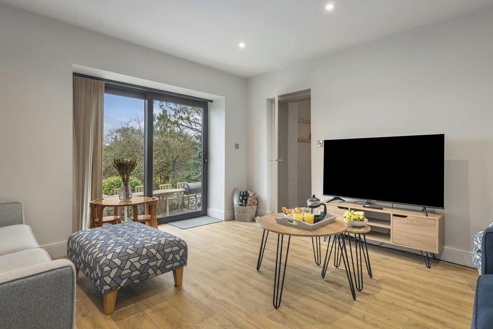 Living room with sofa, patterned ottoman, coffee table and TV on a wooden stand