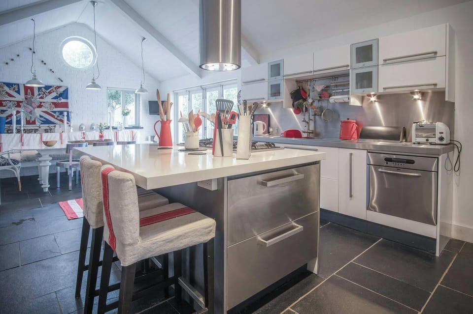 Large island unit with gas hob and extractor hood. Two bar stools