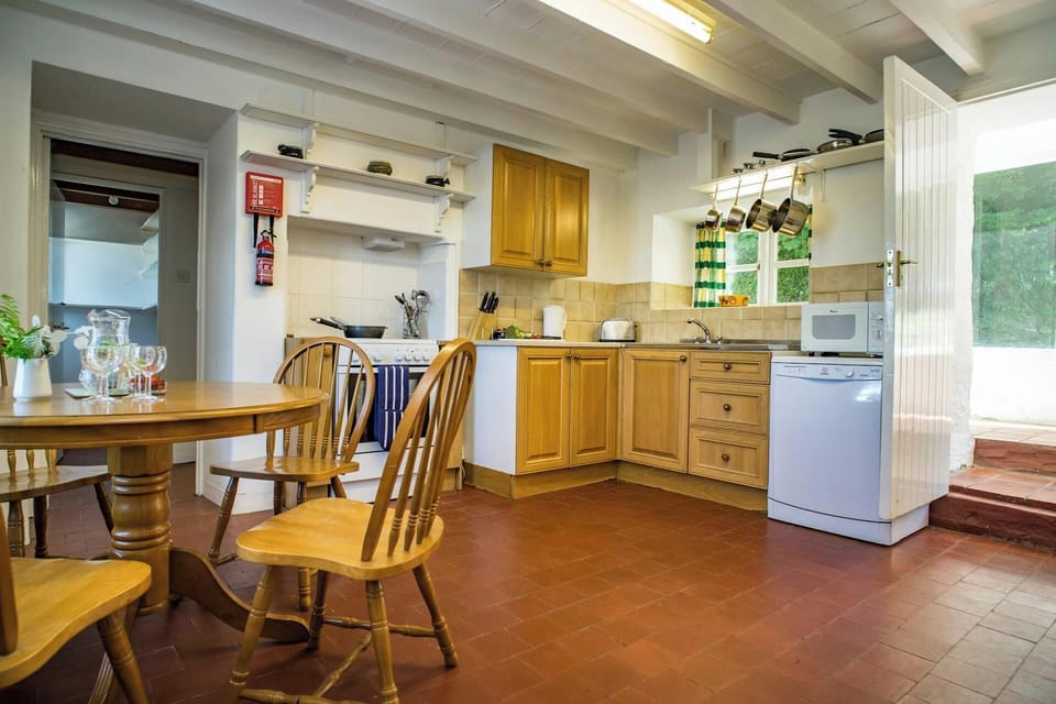 Table and four chairs, oven, dishwasher, microwave, kettle and toaster door to the garden
