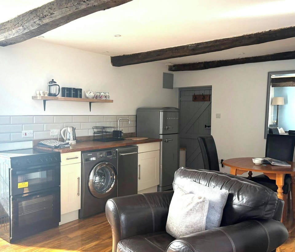 Kitchen area with wood worktop, tiled splashback and freestanding fridge
