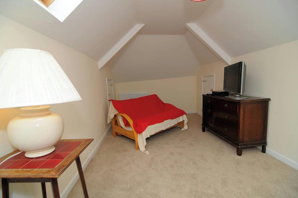 Second living room with sofa-bed, large drawer unit with TV, small table with lamp