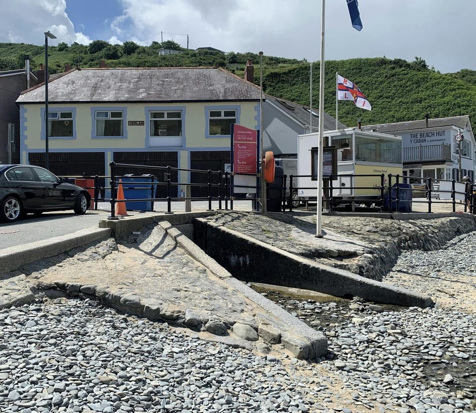 Concrete boat ramp between pebble shore and small stream at the seafront