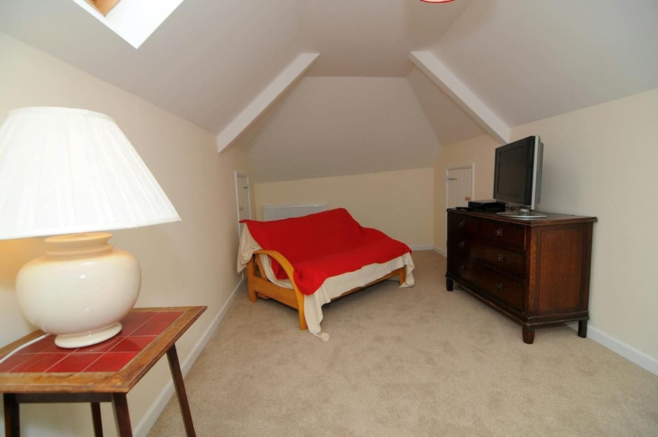 Second living room with sofa-bed, large drawer unit with TV, small table with lamp
