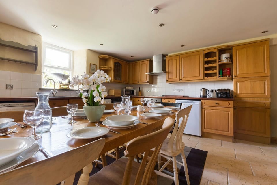 Kitchen/dining area with pine table set for eight, wood kitchen cupboards and dishwasher