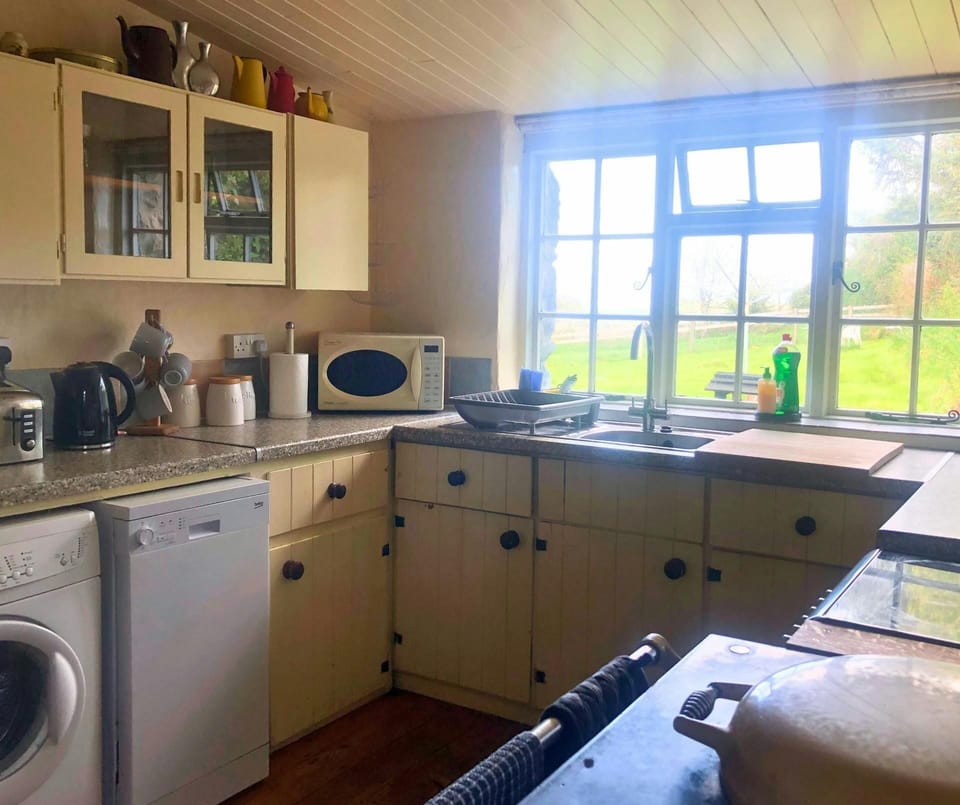 Kitchen with range cooker, washing machine, sink, microwave, kettle, toaster and window overlooking the garden