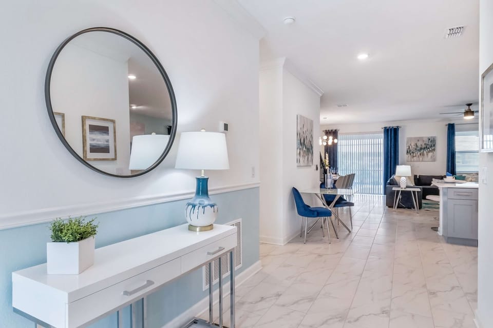 Bright stylish entryway with modern decor, elegant mirror, and open living view
