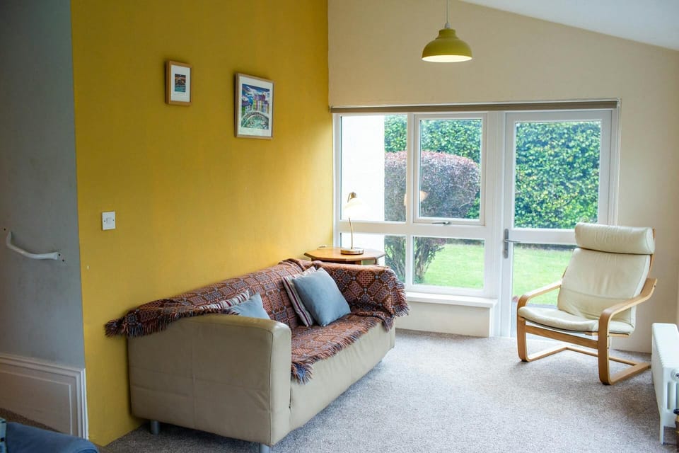 Leather sofa with a Welsh blanket throw. Occasional chair and doors leading to garden