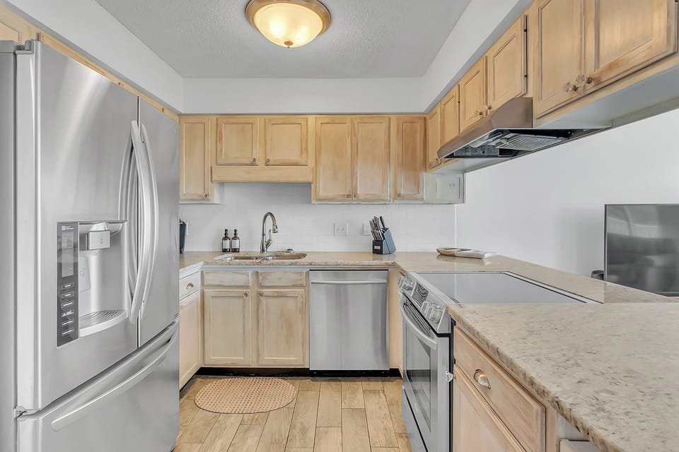Your fully equipped kitchen awaits with stainless steel appliances, granite counters, and warm wood cabinets perfect for preparing memorable meals.