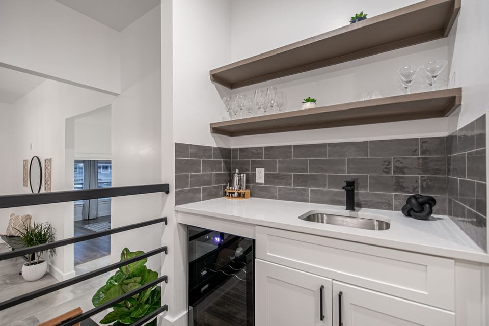 Bar area includes built in beverage fridge, bar tools, wine & martini glasses