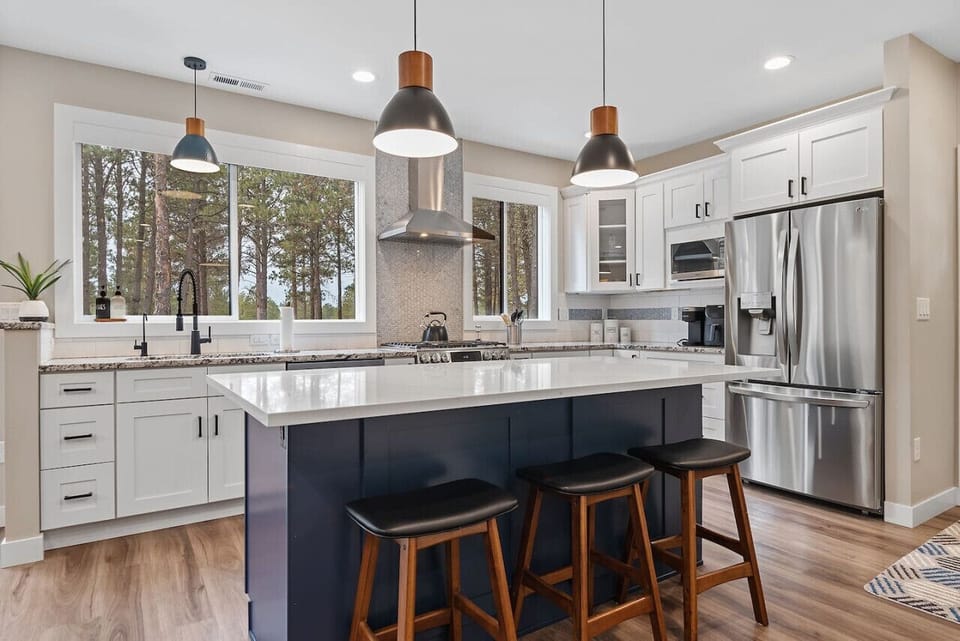 Experience culinary delight in our well-stocked kitchen, complete with a spacious countertop and stools, inviting you to gather, create, and savor delicious meals with ease and convenience.