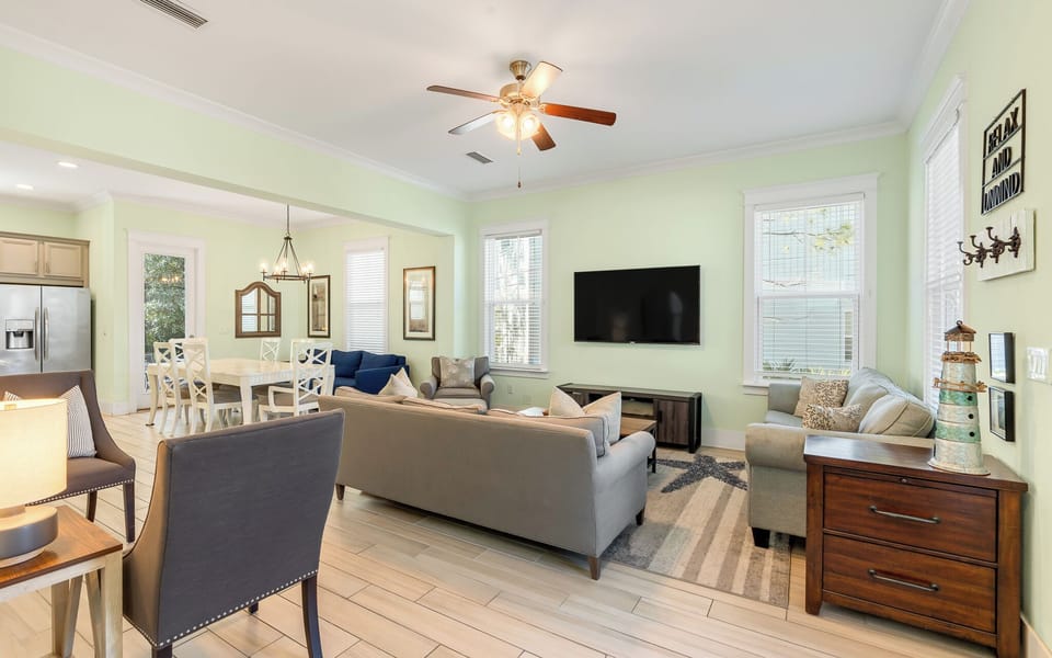 Relax in your spacious open-concept living area with comfortable seating, modern TV, and charming coastal touches throughout.