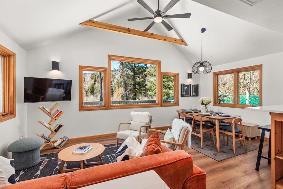 The open-concept living/dining room with large windows framing your riverside oasis