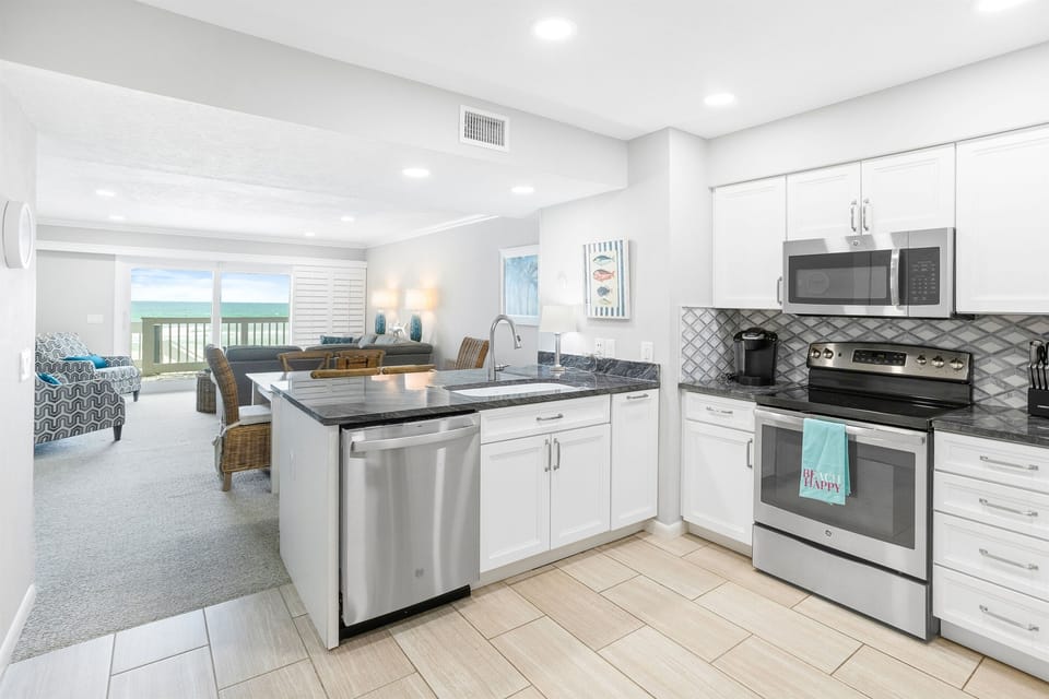 Your modern kitchen flows seamlessly into the bright living area, where ocean views and sleek appliances create the perfect coastal cooking experience.