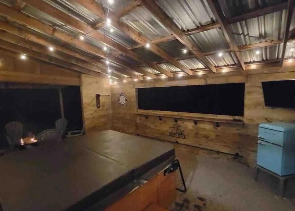 Covered hot tub with TV and minifridge, next to smokeless firepit and seating.
