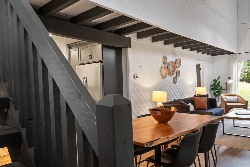 Captured from the stairs, the image showcases the dining table and living area, highlighting the open layout and inviting atmosphere of the space.