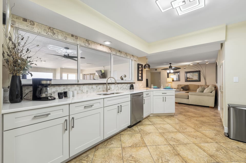 - Spacious kitchen with coffee bar, stainless dishwasher, and wide counters
- Large mirror window opens into the living room for easy entertaining
- Clean white cabinetry and tasteful decor enhance the relaxing layout
