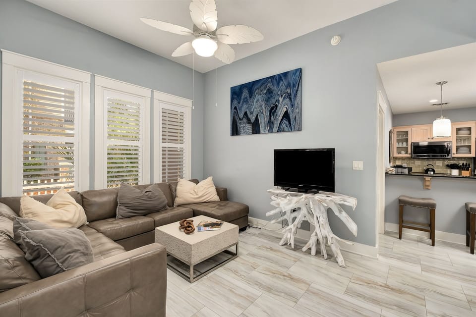 Kick back on the plush sectional, surrounded by serene decor and large windows offering plenty of natural light. The perfect spot for relaxation, with easy access to the kitchen and dining area.