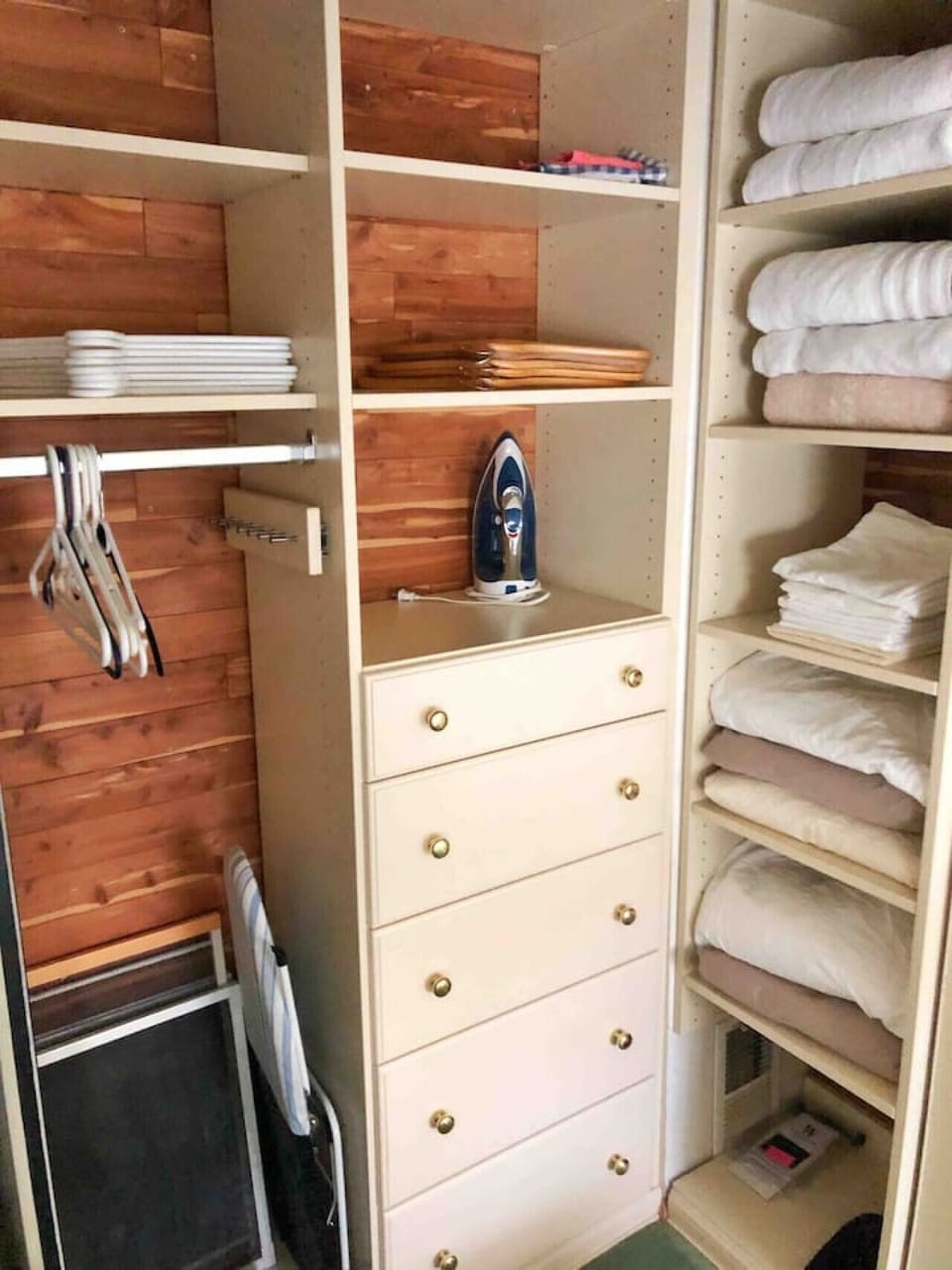 Closet with iron, ironing board, linens, and towels