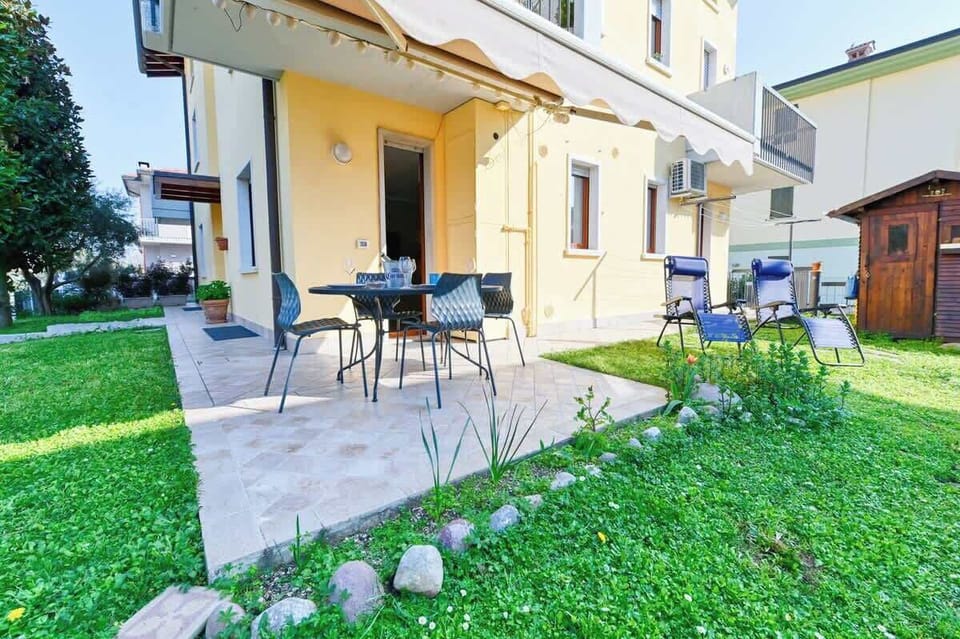 Giardino esterno privato (non recintato) con patio attrezzato con tavolo da esterno, tenda parasole elettrica e sdraio prendisole