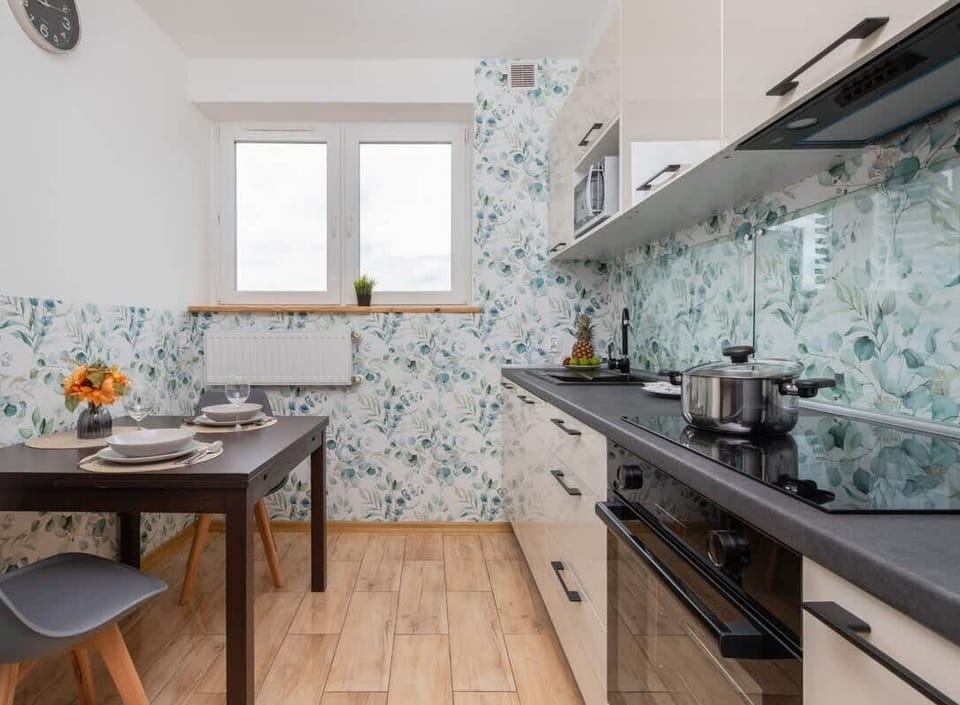 Fully equipped kitchen with upper and lower cabinetry, glass backsplash and dining area.