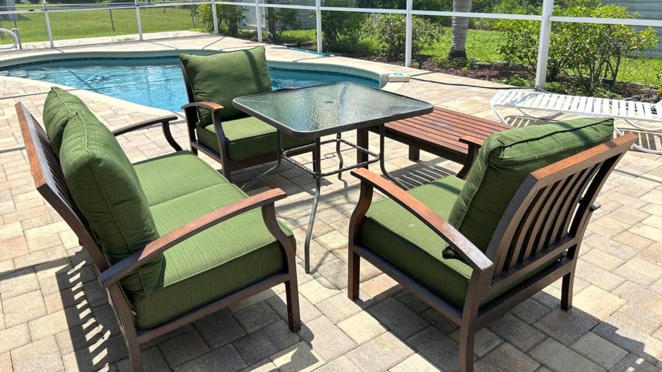 Beautiful, screened-in heated pool featuring chic lounge chairs and a BBQ area.