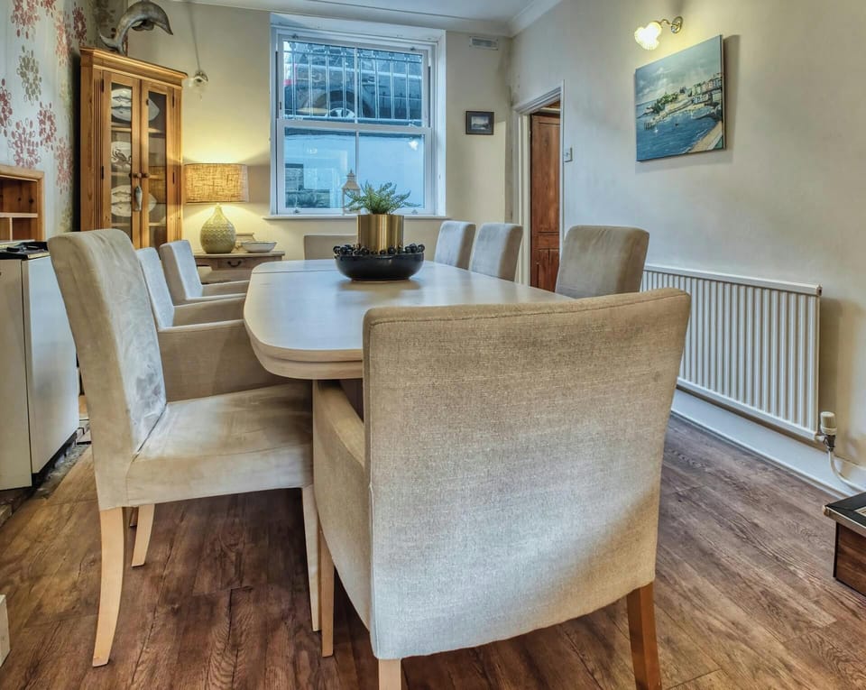 Dining room with table and eight chairs, small table with a lamp and corner storage cupboard
